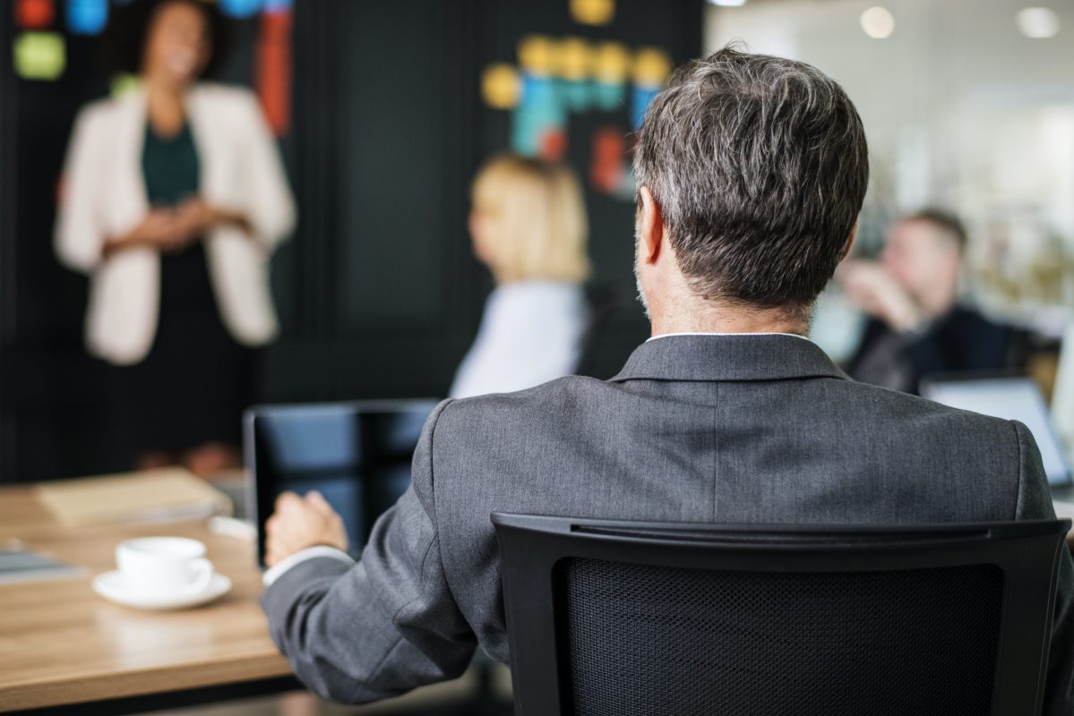 Business people discussing a case with a St. Louis fraud lawyer at a desk.